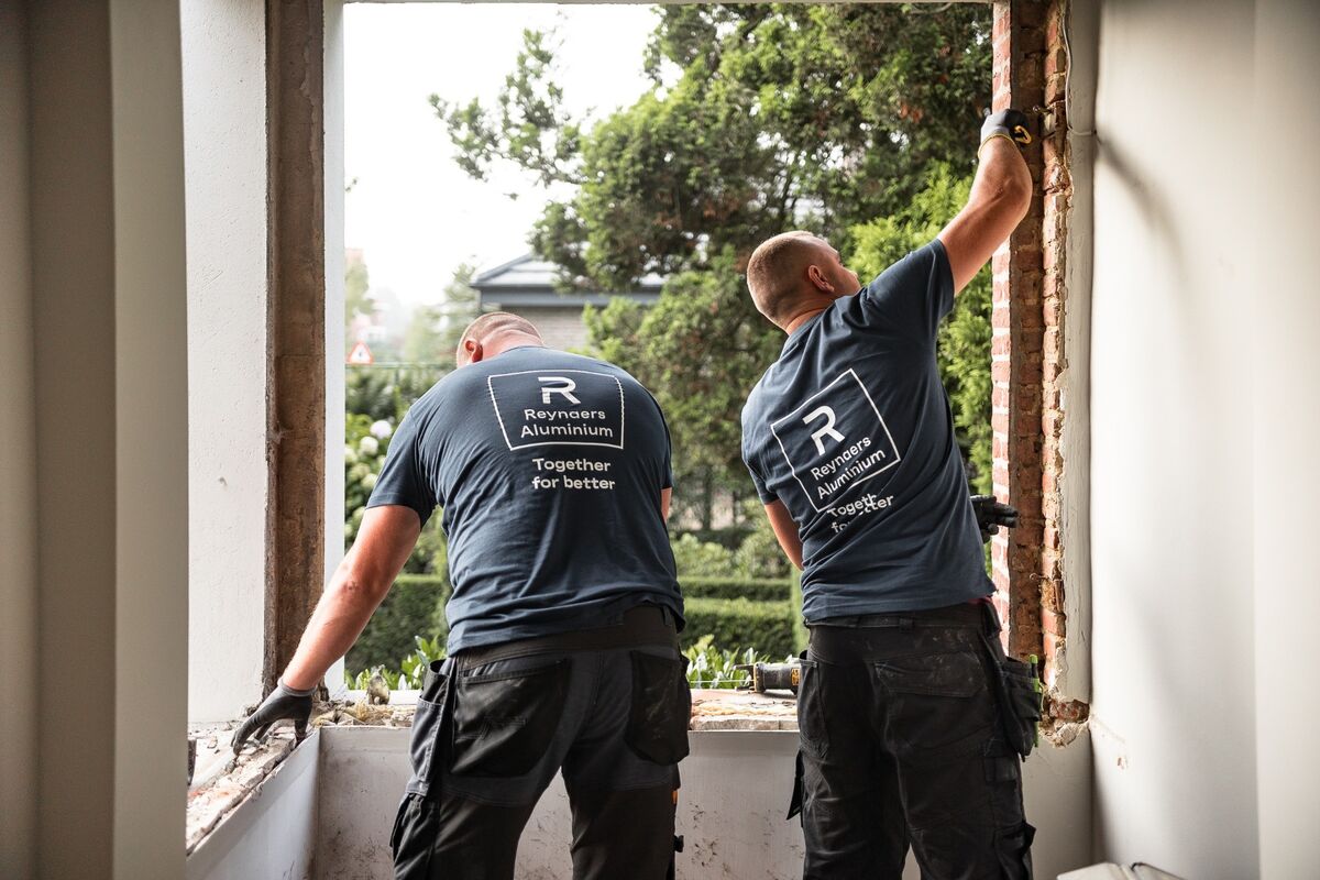 Two Reynaers Aluminium installers dismantling old windows on site.