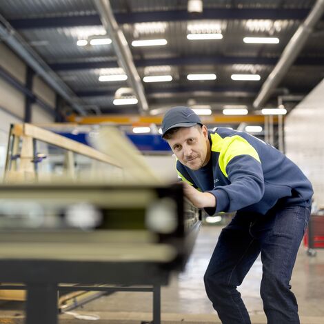 Fabricator aligning window profiles, while wearing safety gear.