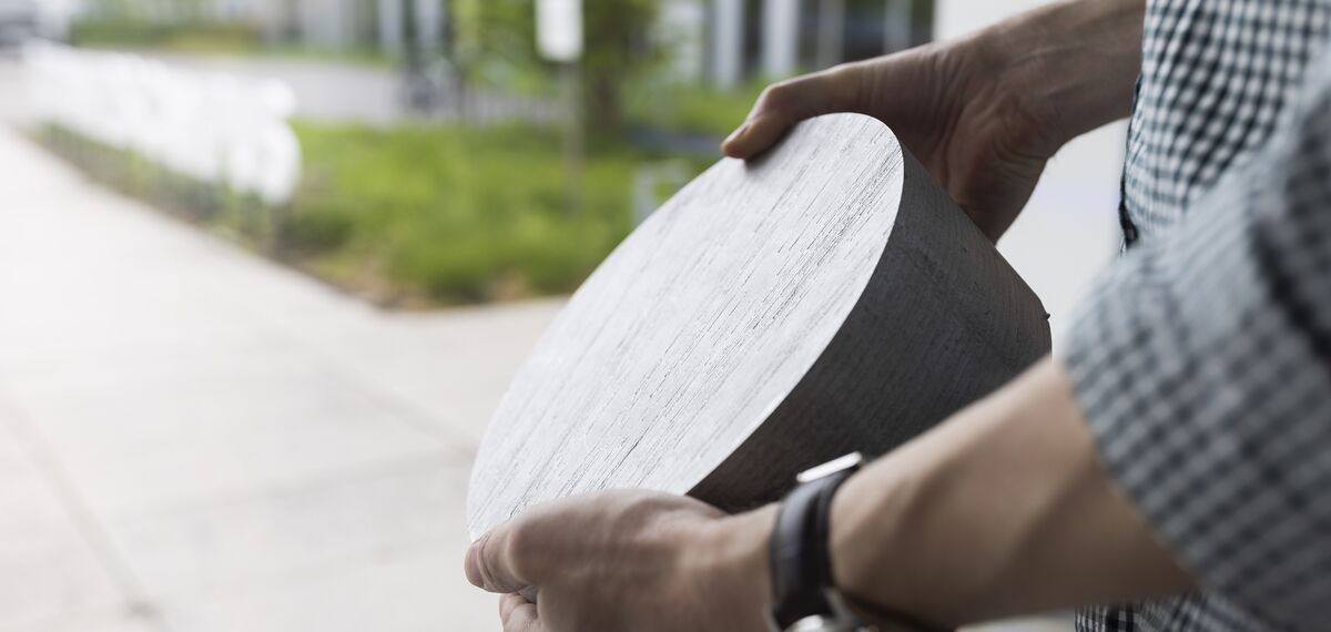 Person holding circular aluminum billet material.