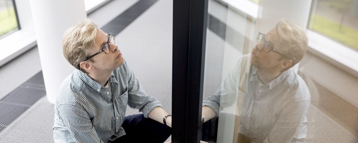 Man with glasses holding black aluminium profile.